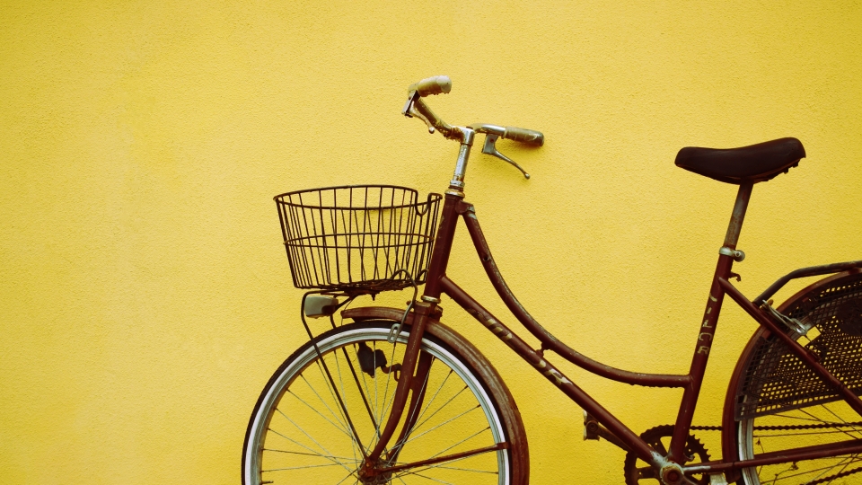 Bicycle resting against a yellow wall