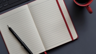 Notebook pen and cup on a desk